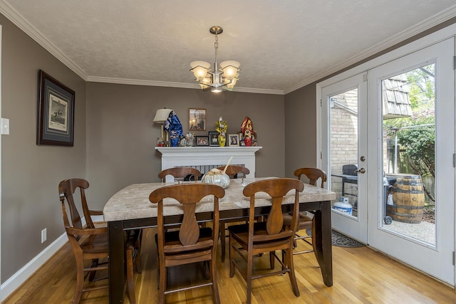 dining room featuring light wood finished floors, ornamental molding, french doors, baseboards, and a notable chandelier