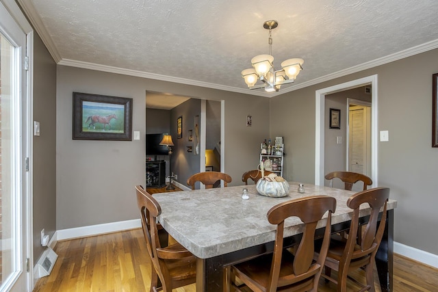 dining space featuring light wood finished floors, baseboards, an inviting chandelier, and crown molding