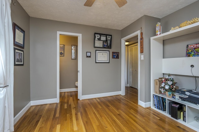 interior space with baseboards, wood finished floors, and a textured ceiling
