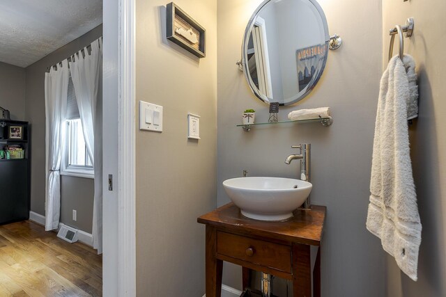 bathroom featuring baseboards, wood finished floors, visible vents, and vanity