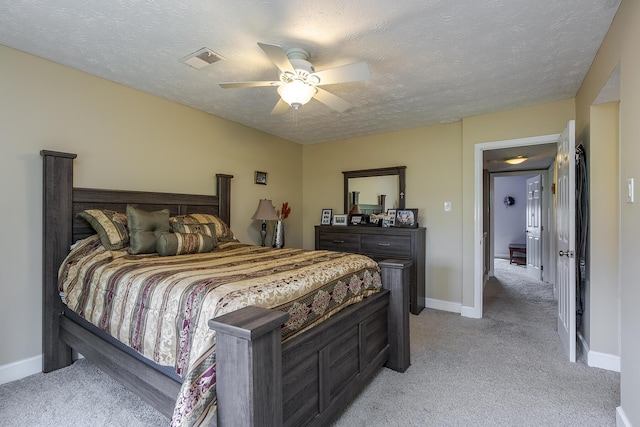 bedroom featuring visible vents, baseboards, a textured ceiling, and light colored carpet