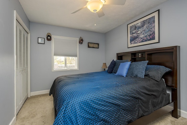 carpeted bedroom with ceiling fan, baseboards, and a closet