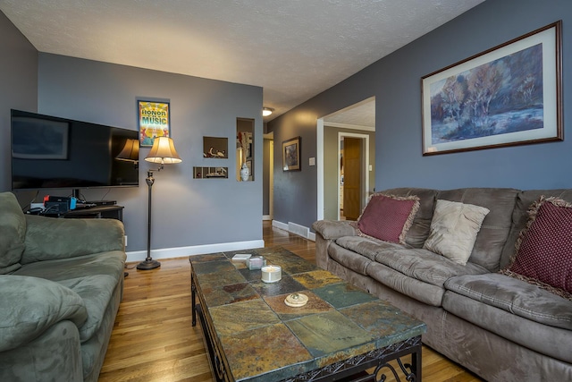 living room featuring a textured ceiling, wood finished floors, visible vents, and baseboards