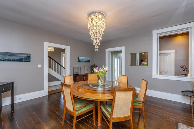 dining area with hardwood / wood-style flooring, baseboards, a chandelier, and stairway