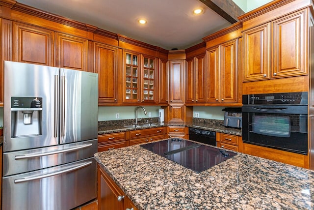 kitchen featuring brown cabinetry, a sink, and black appliances