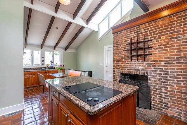 kitchen with brown cabinets, black electric cooktop, visible vents, beamed ceiling, and a kitchen island