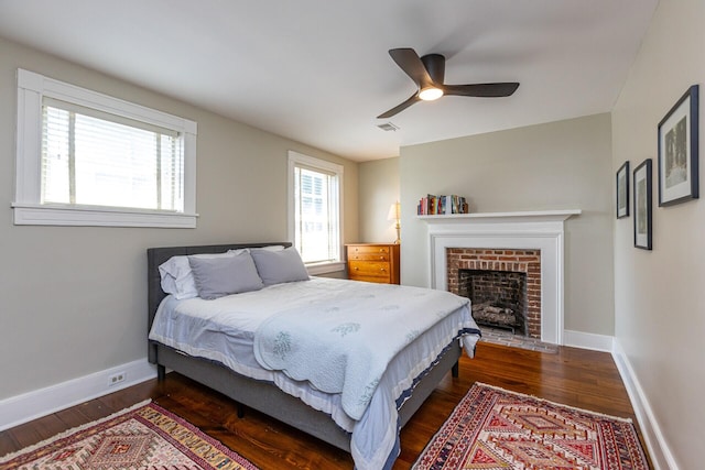 bedroom with visible vents, a ceiling fan, baseboards, a fireplace, and dark wood-style flooring