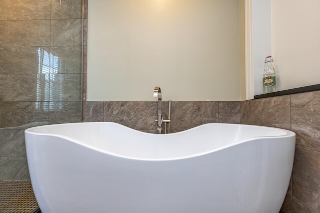 full bath featuring tile walls, a soaking tub, and a sink