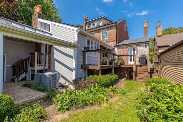 rear view of house featuring brick siding, central air condition unit, a wooden deck, and stairway