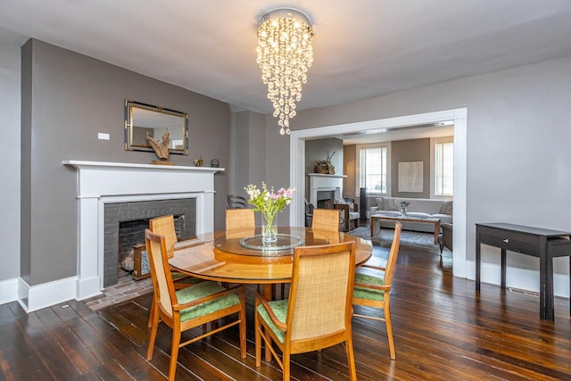 dining space featuring a fireplace with flush hearth, hardwood / wood-style floors, baseboards, and an inviting chandelier