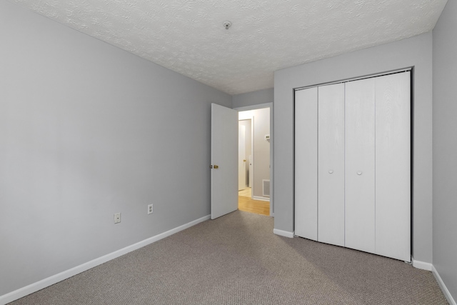 1081 S Broadway Unit 104, Lexington, KY 40504 - unfurnished bedroom with baseboards, carpet flooring, a textured ceiling, and a closet