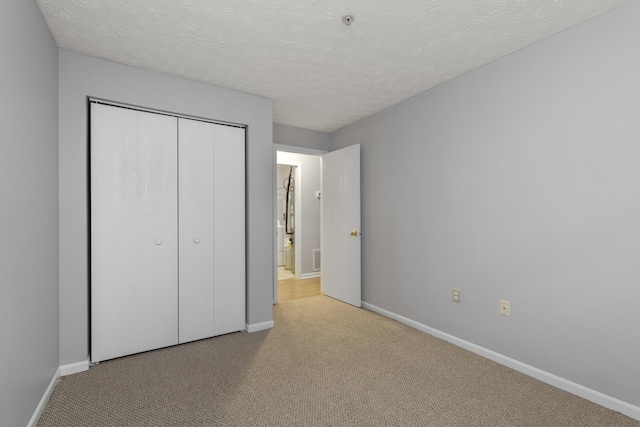 1081 S Broadway Unit 104, Lexington, KY 40504 - unfurnished bedroom with baseboards, carpet flooring, a textured ceiling, and a closet