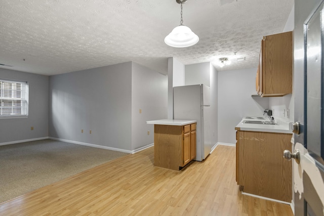 1081 S Broadway Unit 104, Lexington, KY 40504 - kitchen featuring brown cabinets, a sink, freestanding refrigerator, light wood-type flooring, and a textured ceiling