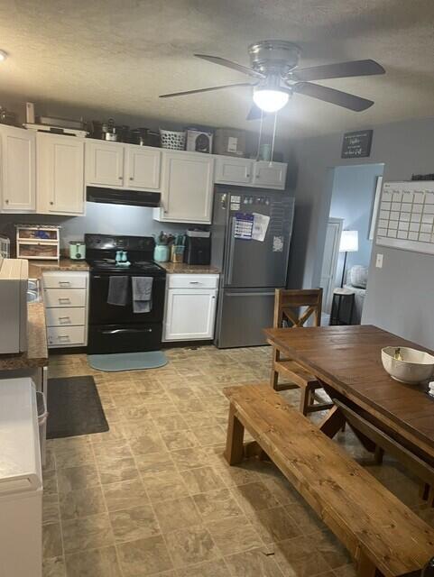 kitchen with freestanding refrigerator, ceiling fan, white cabinetry, and black electric range