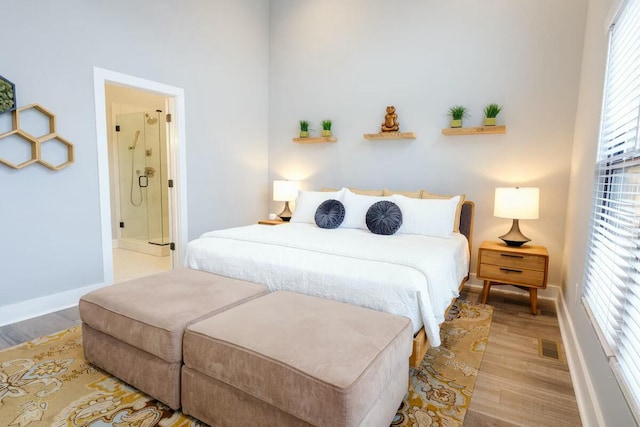 bedroom with baseboards, visible vents, wood finished floors, and ensuite bath