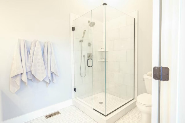 bathroom with baseboards, a shower stall, toilet, and visible vents