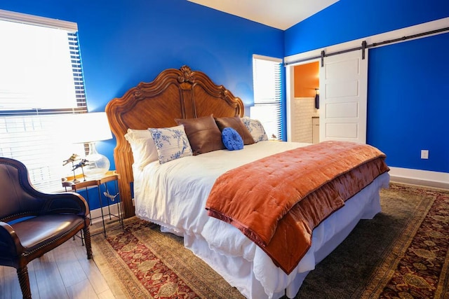 bedroom featuring baseboards, a barn door, and wood finished floors