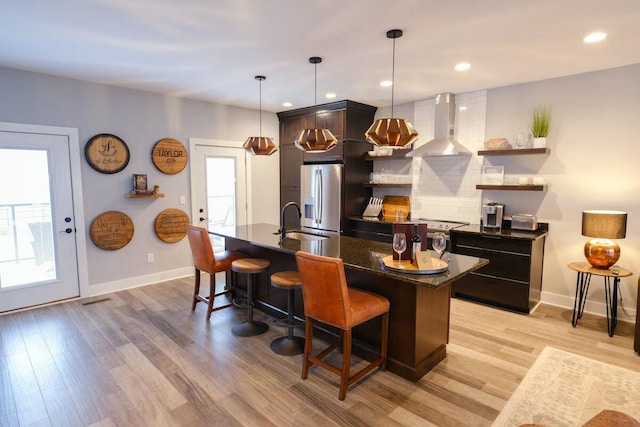 bar with baseboards, wall chimney exhaust hood, stainless steel fridge with ice dispenser, and light wood-type flooring