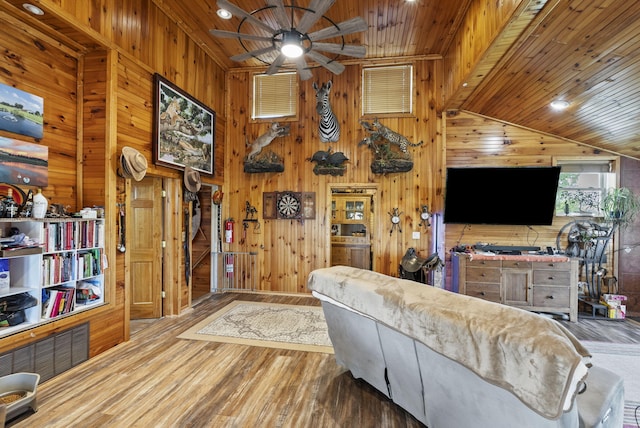 living room with wooden walls, wood ceiling, a ceiling fan, and wood finished floors
