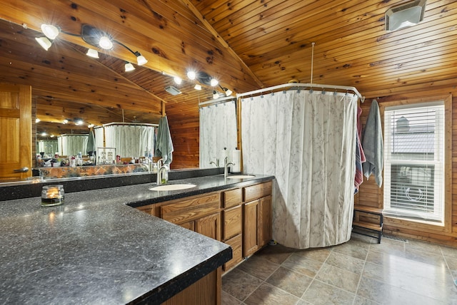 kitchen with wooden walls, a sink, and lofted ceiling