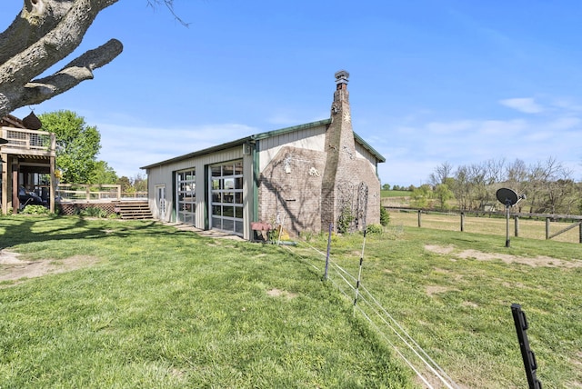exterior space featuring fence, a deck, a chimney, a lawn, and an outbuilding