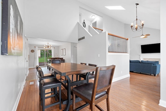 dining space with high vaulted ceiling, visible vents, light wood finished floors, and a notable chandelier