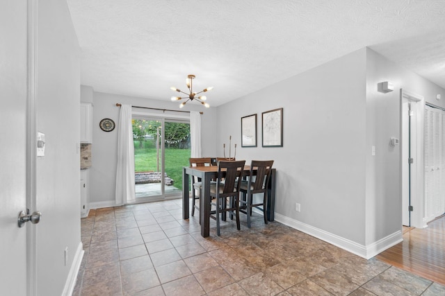 dining area featuring baseboards, a textured ceiling, and a notable chandelier