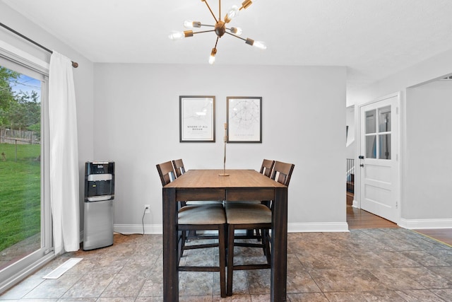 dining area featuring baseboards, a notable chandelier, and stone finish floor