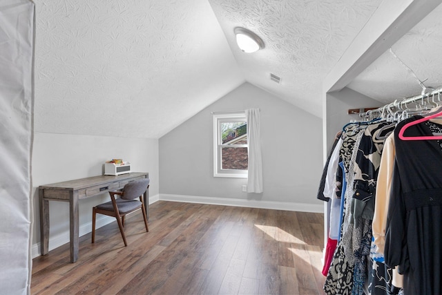 walk in closet with visible vents, lofted ceiling, and wood finished floors
