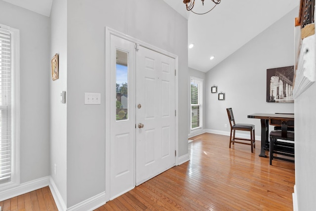 entrance foyer with an inviting chandelier, baseboards, high vaulted ceiling, recessed lighting, and light wood-style flooring