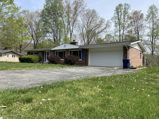 ranch-style house featuring a chimney, a front lawn, an attached garage, driveway, and brick siding