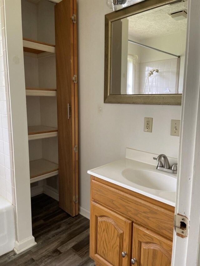 full bathroom featuring wood finished floors, vanity, a bathtub, walk in shower, and baseboards