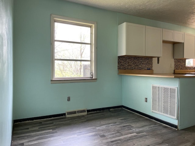 kitchen featuring decorative backsplash, wood finished floors, visible vents, and a textured ceiling