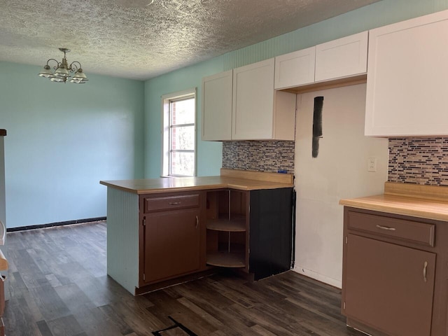 kitchen featuring a peninsula, a textured ceiling, dark wood finished floors, and tasteful backsplash