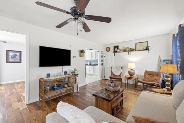 living room with ceiling fan, baseboards, and wood finished floors