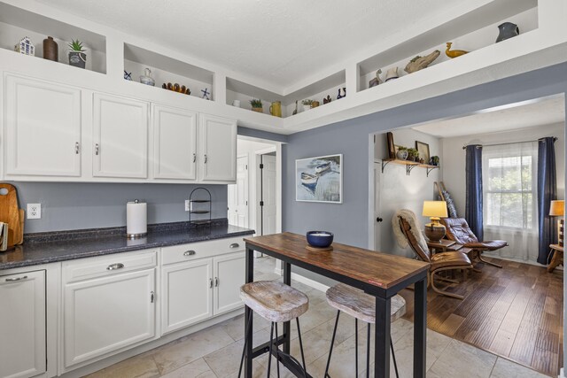 kitchen with dark stone countertops, white cabinetry, and open shelves