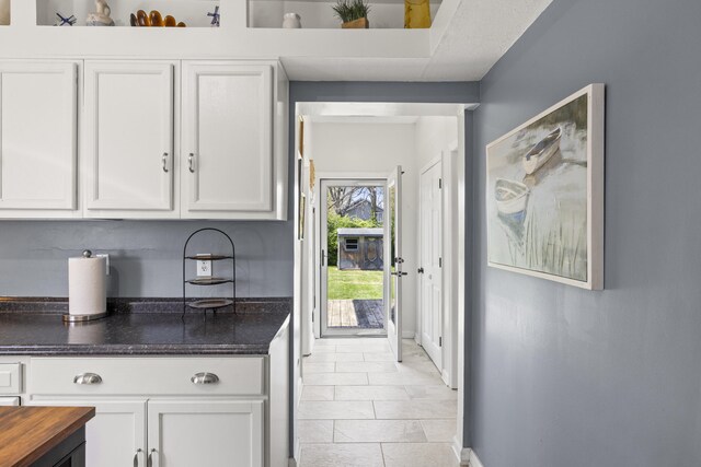 kitchen featuring light tile patterned flooring, baseboards, wooden counters, and white cabinetry