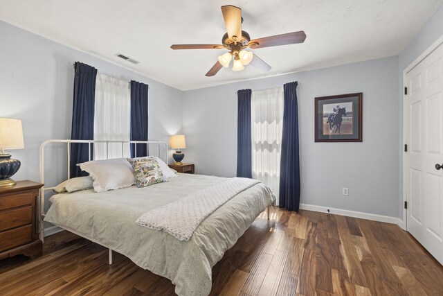 bedroom with baseboards, wood finished floors, visible vents, and ceiling fan