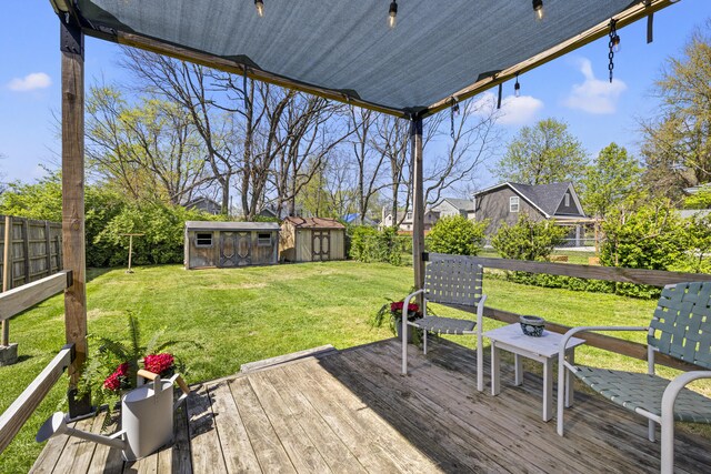 deck with a storage shed, a lawn, a fenced backyard, and an outdoor structure