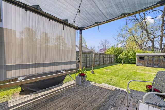 deck featuring an outdoor structure, fence, and a yard