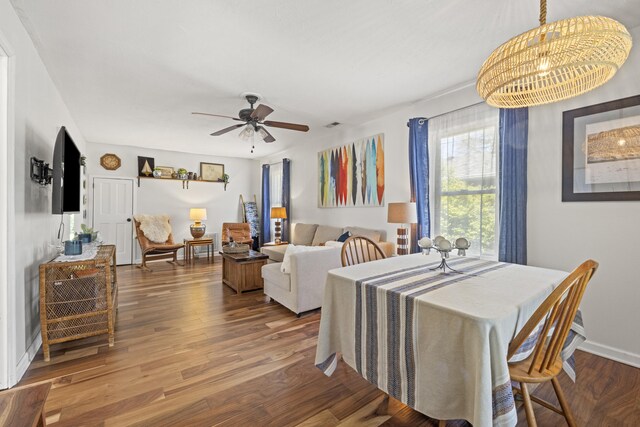 dining space with wood finished floors, baseboards, and ceiling fan with notable chandelier