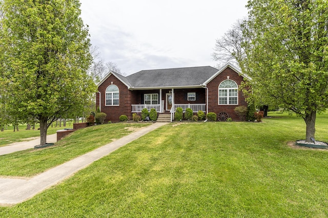 ranch-style home featuring covered porch, brick siding, a shingled roof, and a front yard