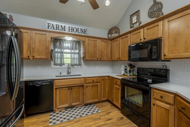 kitchen with a textured ceiling, tasteful backsplash, a sink, light countertops, and black appliances