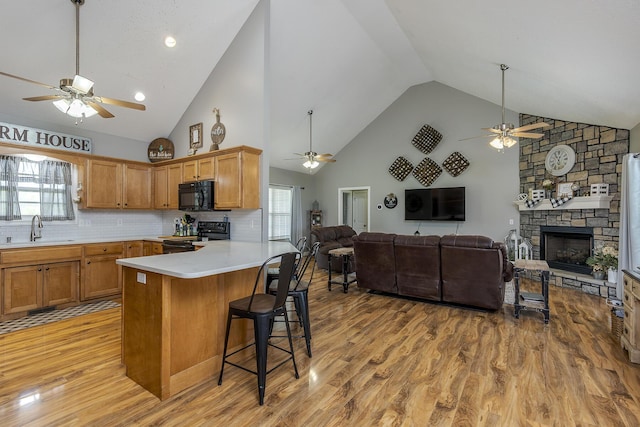 kitchen with black appliances, a ceiling fan, a sink, and open floor plan