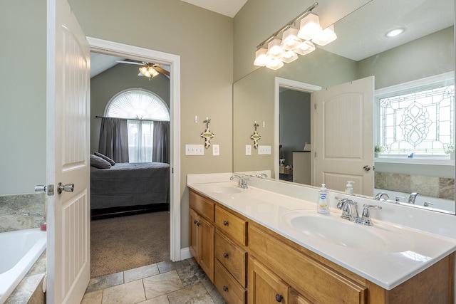 ensuite bathroom featuring double vanity, a sink, a relaxing tiled tub, and connected bathroom