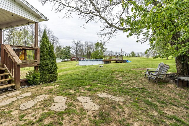 view of yard with an outdoor pool, stairs, and a deck