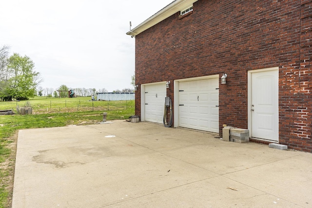 garage with fence and concrete driveway