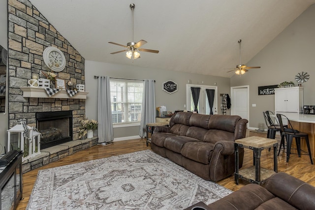 living area featuring a ceiling fan, high vaulted ceiling, baseboards, and a fireplace