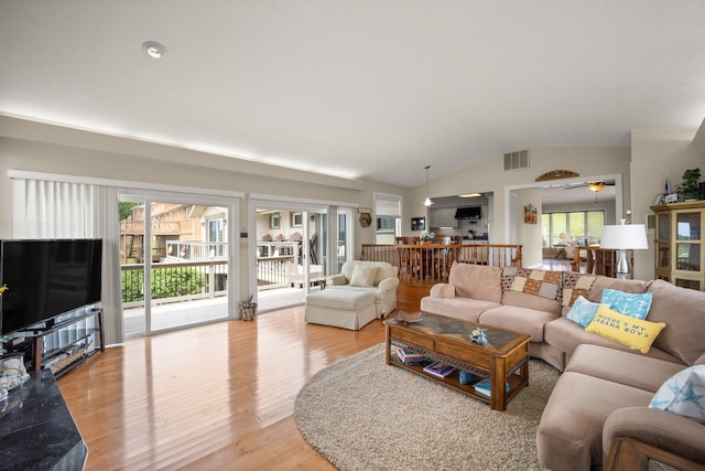 living area featuring visible vents, light wood-style floors, and lofted ceiling