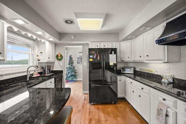 kitchen featuring light wood-style floors, ventilation hood, white cabinetry, a sink, and black appliances